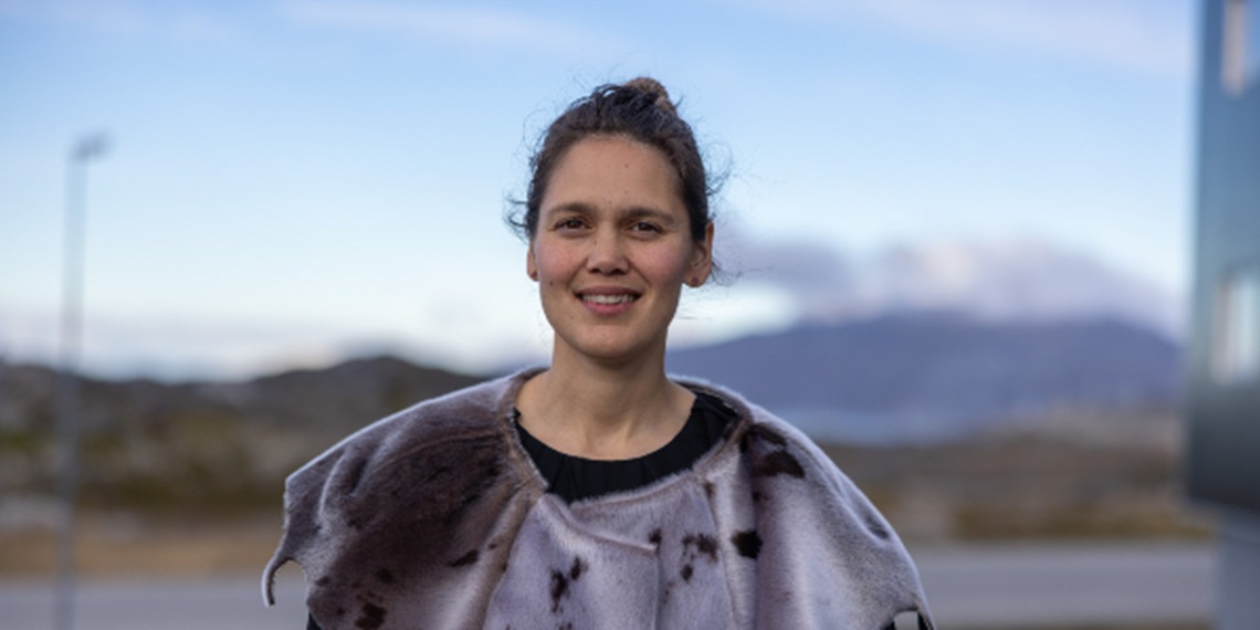 Trine står foran Sermitsiaq med en sælskindskappe.